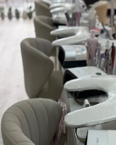 Row of manicure tables with nail lamps and blush velvet chairs