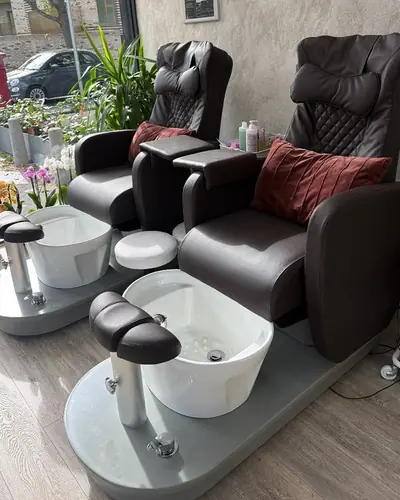 Pedicure spa chairs with foot basins beside the salon's front window