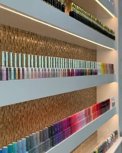Close-up of gel polish colours lined up in front of the salon's gold hexagon wall