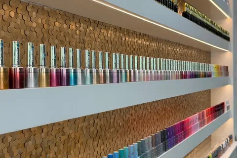 Close-up of gel polish colours lined up in front of the salon's gold hexagon wall