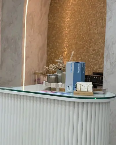 Reception desk with a fluted white front and glass top beside a textured gold and cream wall