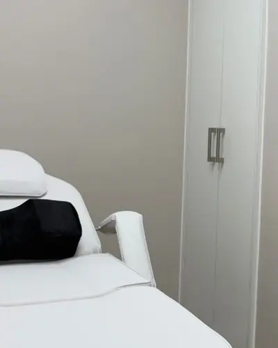 Private treatment room with a white beauty couch, marble-topped counter and wall mirror