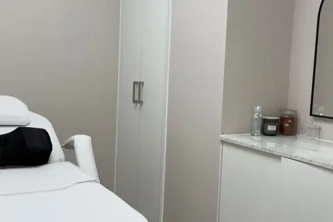 Private treatment room with a white beauty couch, marble-topped counter and wall mirror