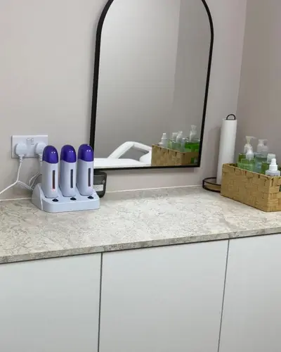 Waxing room counter with wax heaters, a marble splashback and a bronze vessel basin