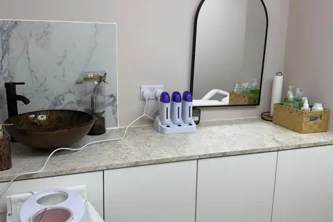 Waxing room counter with wax heaters, a marble splashback and a bronze vessel basin
